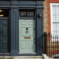 an etch effect custom house door number sticker stuck on to a window above a pale green front door.